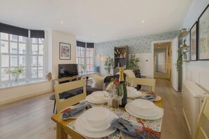 A dining area with a table set for four, a television, and a bookshelf.