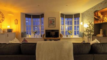 Una sala de estar acogedora con un sofá, un televisor y objetos decorativos.
