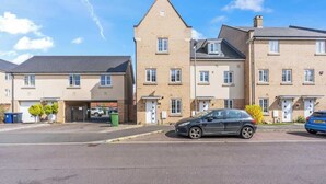 Une rue résidentielle bordée de maisons à deux étages, chacune ayant un garage et une porte d’entrée.