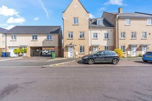 A residential street with a row of two-story houses, each with a garage and a front door. - Stylish 4 Bedroom House in St Neots w Free Parking (Cambridgeshire)