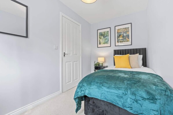 A bedroom with a bed, a nightstand, a lamp, and two framed pictures on the wall.