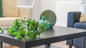 Un salon moderne avec une table basse en bois foncé, un vase en verre vert et une plante verte.