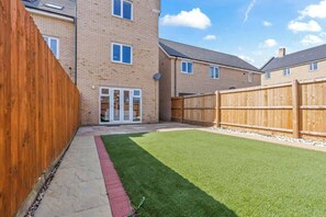 Un quartier résidentiel avec un bâtiment en briques, une clôture en bois et une pelouse bien entretenue.