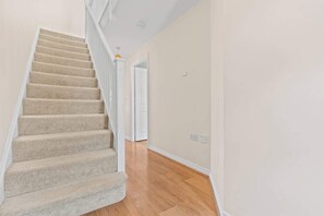 A carpeted staircase leading to a second floor, with a wooden floor and white walls.