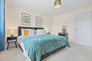 Une chambre à coucher avec un lit, des tables de chevet, une armoire et une porte.