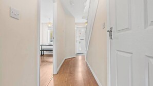 Un couloir étroit doté d’un plancher en bois et de murs blancs.
