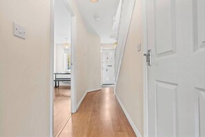 A narrow hallway with wooden flooring and white walls. - Stylish 4 Bedroom House in St Neots w Free Parking (Cambridgeshire)