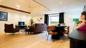 Una sala de estar moderna con sofá, sillas, televisor y una mesa de comedor.