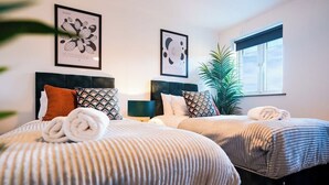 Habitación de hotel con dos camas, un ventanal grande y obras de arte en las paredes.