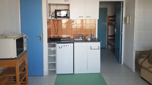 A compact kitchen with white cabinets, a microwave, and a sink.