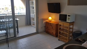 A small kitchenette with a microwave, a wooden cabinet, and a table with chairs.