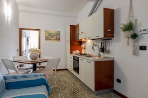 Une cuisine compacte avec des meubles blancs, un plan de travail en bois et un coin repas comprenant une table et des chaises.