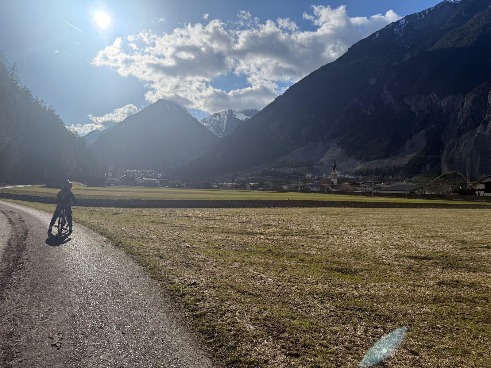 A cyclist on a paved path with a mountain landscape in the background.
