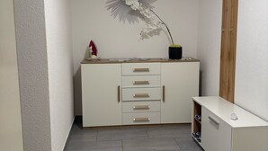A modern, minimalistic room with a white cabinet, a decorative mirror, and a potted orchid.