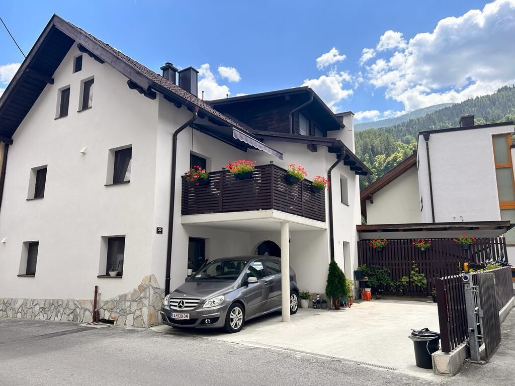 A two-story house with a car parked in the driveway.