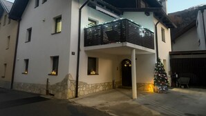 A two-story house with a balcony, stone foundation, and a Christmas tree.