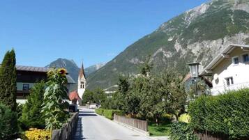 A street with houses, a church, and mountains in the background.