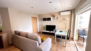 Una sala de estar moderna con un sofá, televisión, mesa de comedor y sillas.