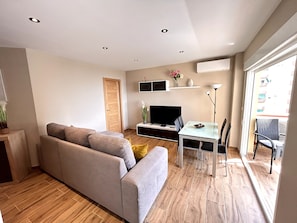 A modern living room with a sofa, TV, dining table, and chairs.