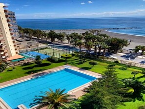 A hotel with a swimming pool, a beach, and a view of the ocean.