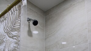 Um chuveiro com cortina florida, um chuveiro manual e um painel de comando fixado na parede.