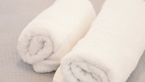 Two rolled white towels placed on a textured surface. - Arion apartment (Athina)