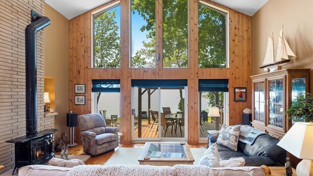 Un salon spacieux doté d’une grande fenêtre à cadre en bois, d’une cheminée et d’un coin salon confortable.