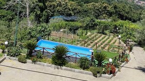 A mountainous landscape with a clear sky. There is a blue-roofed building in the foreground, surrounded by greenery and a pool area. - Nature room, double room with private bath 20 Min from Pompeii, 40 from amalfi (Campania)