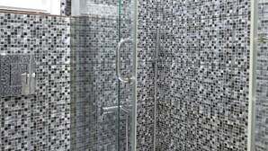 A shower with a glass door and mosaic tile walls. - Estia apartment (Athina)