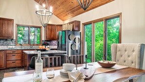 Une cuisine moderne avec des meubles en bois, un grand îlot central et un coin repas avec une table dressée pour deux personnes.