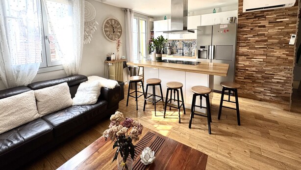 A modern living room with a black leather sofa, a wooden coffee table, and a kitchen area with a bar stool set. - Balcon de la Providence (Niza)