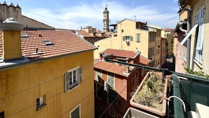 A narrow street with buildings featuring red-tiled roofs and balconies. - Balcon de la Providence (Niza)