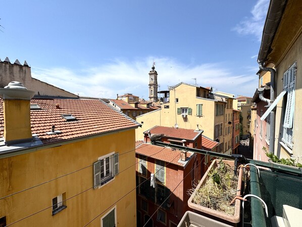 Une rue étroite bordée d’immeubles aux toits recouverts de tuiles rouges et dotés de balcons.