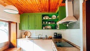A modern kitchen with wooden ceiling beams, green cabinets, and a central island with a sink. - Santa Sofia. Casa com 4 quartos e Jardim Espaçoso em Moledo (Moledo)
