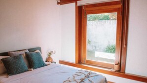 A bedroom with a bed, pillows, a window, and a small plant. - Santa Sofia. Casa com 4 quartos e Jardim Espaçoso em Moledo (Moledo)