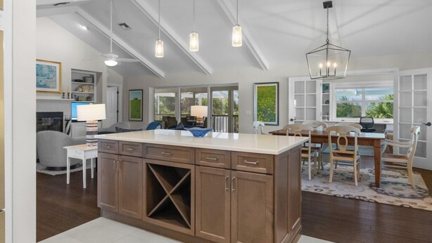 A spacious kitchen with a large island, pendant lighting, and a dining area with a view of the outdoors.