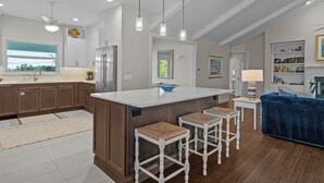 A modern kitchen with a central island, bar stools, and pendant lighting.
