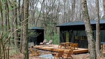 Une cabane dotée d’une terrasse en bois, d’un coin salon et d’un espace extérieur abrité.