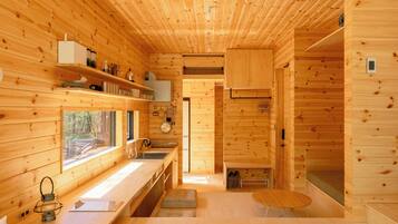 L’intérieur d’une cabane en bois comprend un coin cuisine, une table à manger et une fenêtre donnant sur l’extérieur.