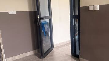 Habitación con suelo de baldosas, una puerta entreabierta y un interruptor de luz en la pared.