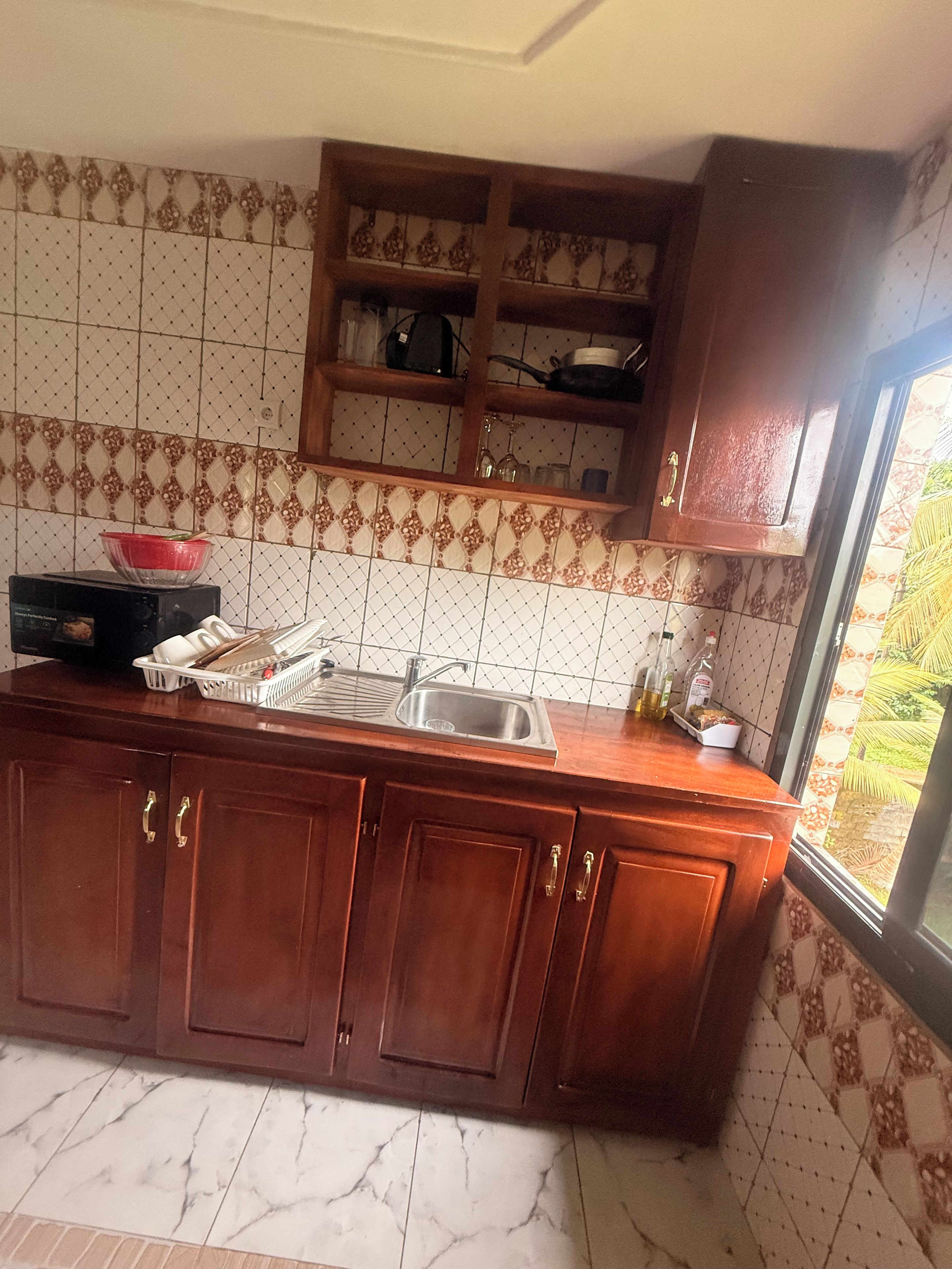 Una cocina con armarios de madera, un fregadero y un ventanal con vistas a follaje.