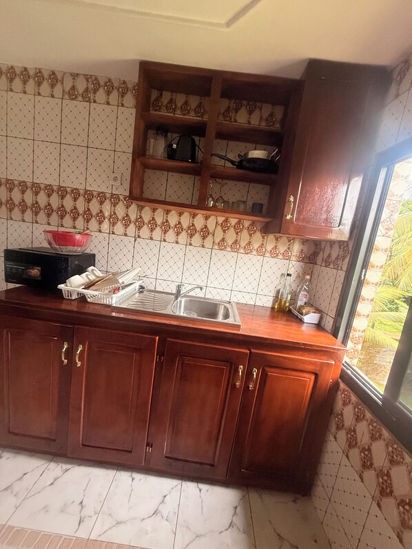 A kitchen with wooden cabinets, a sink, and a window with a view of greenery.
