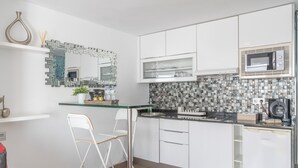 A modern kitchen with white cabinets, a glass countertop, a microwave, and a tiled backsplash. - 'Kikere Puerto del Carmen' Holidays with Shared Pool, Wi-Fi and Air Conditioning (Puerto del Carmen)