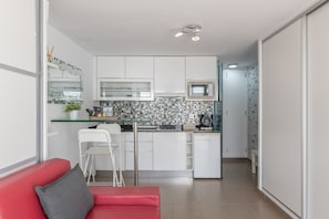 Une cuisine moderne avec des meubles blancs, un four à micro-ondes et un pare-feu en carreaux.