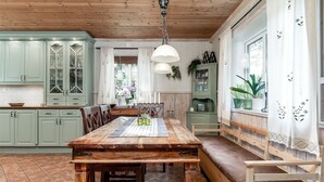 Een landelijke keuken met een houten tafel, groene kastjes en een bank.
