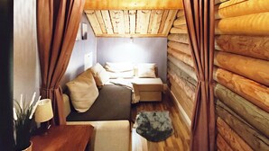 Een gezellig kamer in een blokhut met een bed, een klein tafeltje en een lamp.