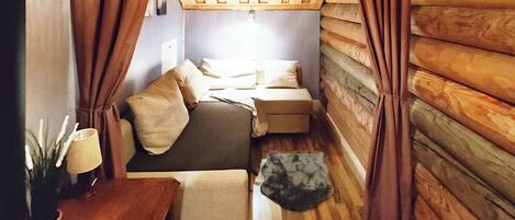 A cozy cabin room with a bed, a small table, and a lamp.