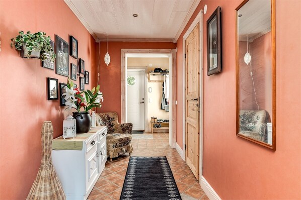 A hallway with a wooden door, a mirror, and a door with a coat rack.