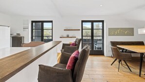 A modern kitchen with a wooden countertop, a dining area with a wooden table and chairs, and a large window with a view of the outdoors. - Spacious Allgäu loft | maisonette style (Nesselwang)