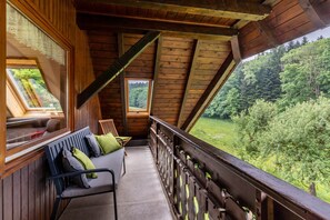 A wooden cabin with a balcony, a bench, and a view of a forest. - Apartment 'Vogelnest' with Mountain View, Shared Pool and Wi-Fi (Wolfach)